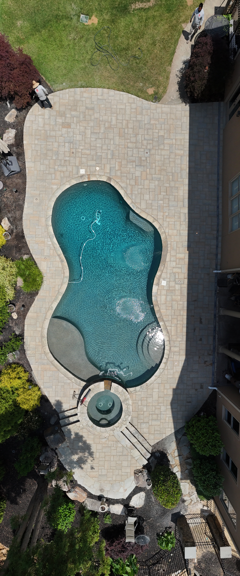 Tall aerial panorama of freeform pool, spa, and travertine paver deck